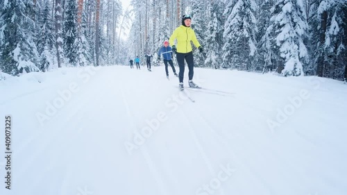 Cross country ski. Group of skiers work out on the skating ski track in the winter forest with snow covered trees