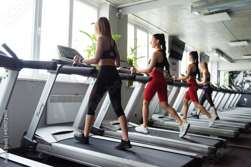 Two active women doing cardio on treadmill at gym