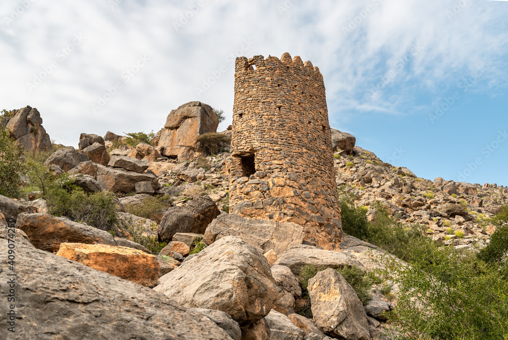 Tower ruins with Omani flag into the hills of the old village Misfat Al Abriyeen, Sultanate of Oman