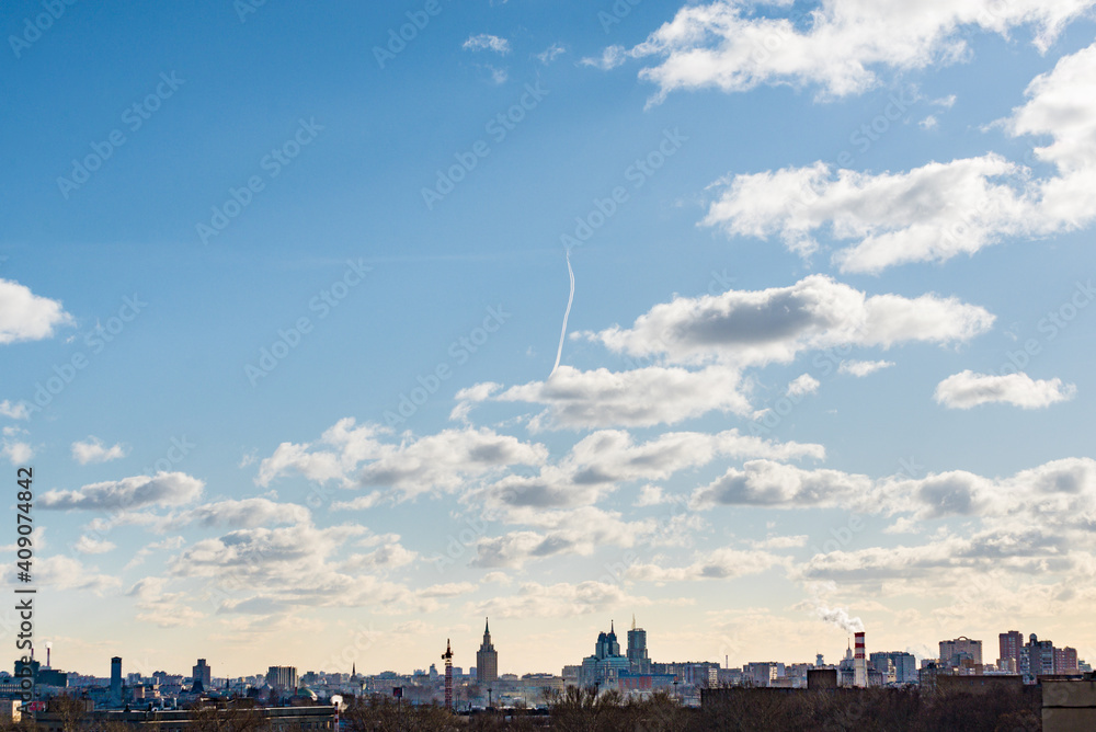 Fototapeta premium airplane flies in white clouds in a blue sky and leaving trail