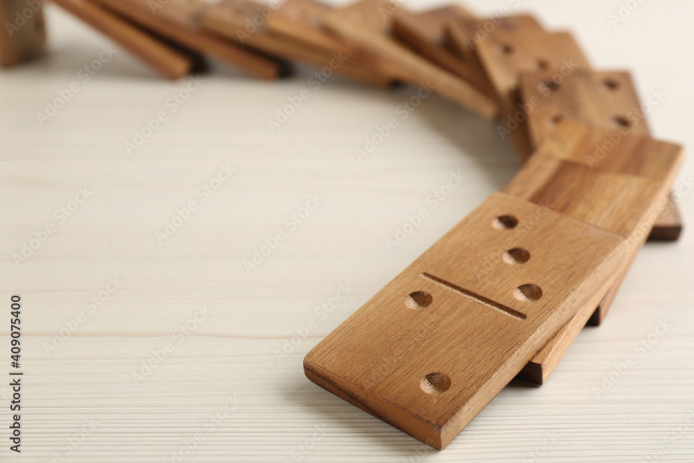 Fallen wooden domino tiles on white table, closeup Fallen wooden domino tiles on white table, closeup