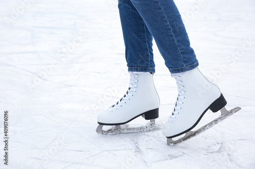 Woman wearing figure skates on ice rink, closeup. Space for text