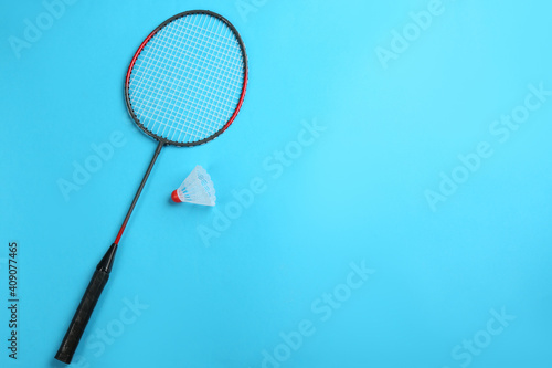Racket and shuttlecock on light blue background, flat lay with space for text. Badminton equipment
