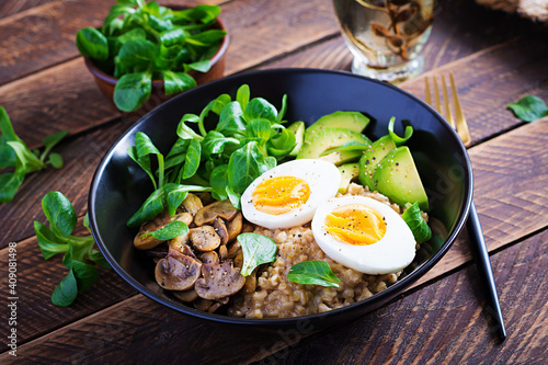 Breakfast oatmeal porridge with boiled egg, avocado and fried mushrooms. Healthy balanced food.