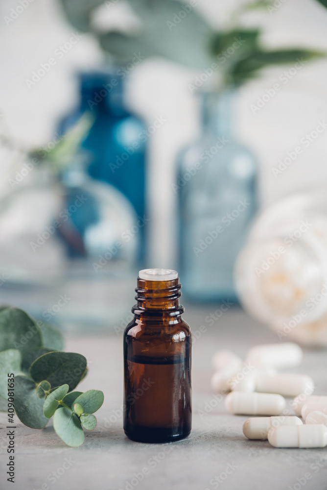 Eucalyptus essential oil and fresh leaves, white capsules pills on the stone board. Eucalyptus essential oil and fresh leaves, white capsules pills on the stone board.
