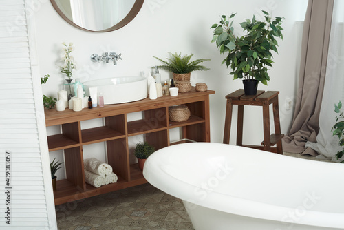 Stylish interior of bathroom with green houseplants. Empty bathtub in an empty bathroom