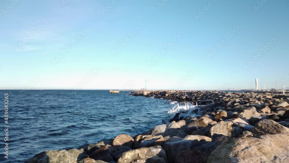 4K Pan over Oresund, Malmo, Sweden. Rocks on shore, frozen icy pier, view of turning torso. 4K Pan over Oresund, Malmo, Sweden. Rocks on shore, frozen icy pier, view of turning torso.