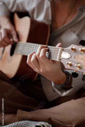 Man playing acoustic guitar at home on bed cozy