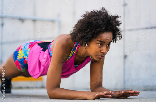 Afro athlete woman doing pushups outdoors.
