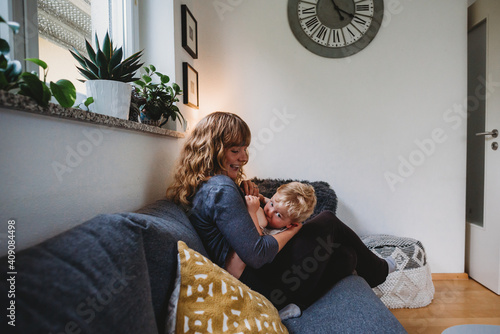 Boy breastfeeding at home with mom smiling in living room photo