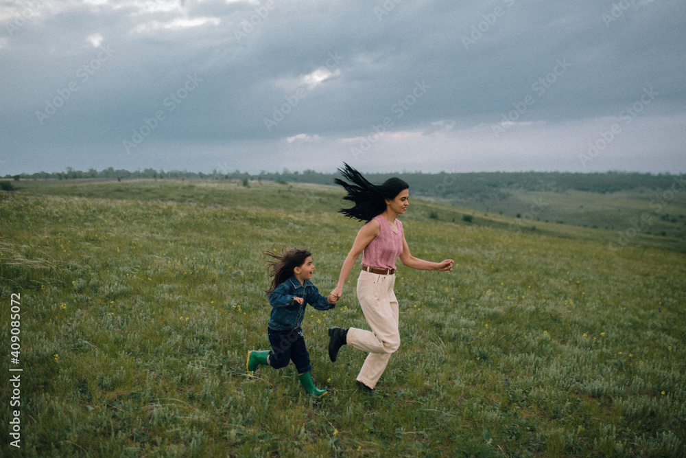 mom and daughter running down hill in countryside mom and daughter running down hill in countryside
