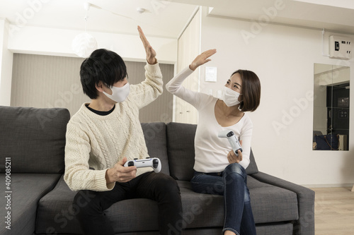 Couple wearing masks enjoying the latest video games / Couple wearing masks enjoying video games with lovers wearing masks / Couple wearing masks crazy about video games  photo