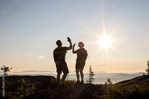 Two hikers high five and celebrate reaching summit of mountain, Maine