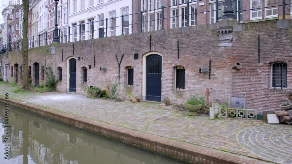 Utrecht canals showing brickwork wharfs lined with trees and plants, and historic wharf cellars with blue doors Utrecht canals showing brickwork wharfs lined with trees and plants, and historic wharf cellars with blue doors