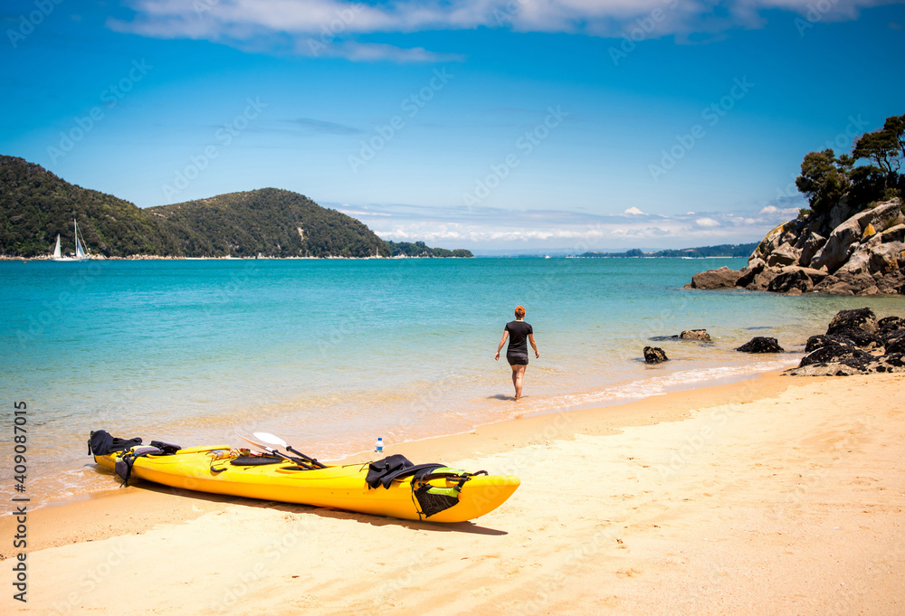Woman exploring sandy beach with kayak in Abel Tasman National Park Woman exploring sandy beach with kayak in Abel Tasman National Park