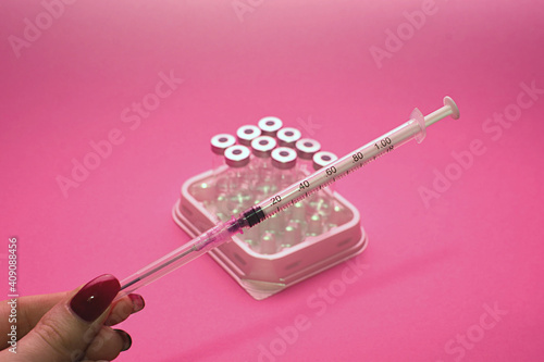 three ampoules with medicine and a syringe on a pink background. human and veterinarian medicine concept
