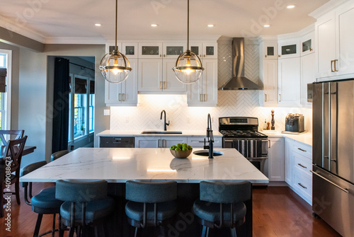 Modern kitchen with white cupboards, dark island and gold accents. photo