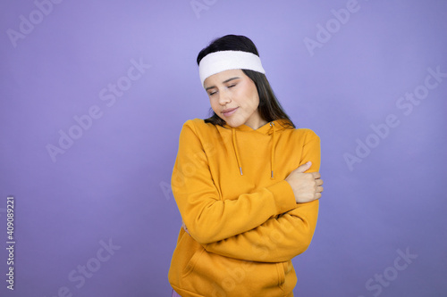 Young latin woman wearing sportswear over purple background hugging oneself happy and positive, smiling confident
