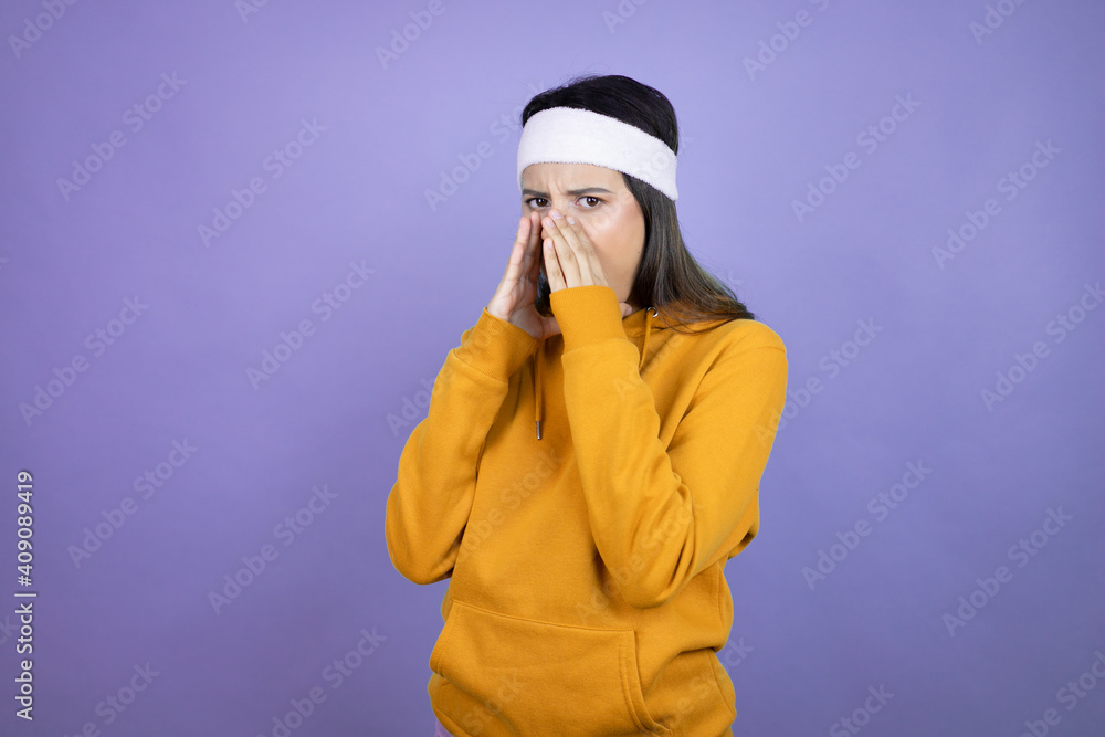 Young latin woman wearing sportswear over purple background shouting and screaming loud to side with hands on mouth