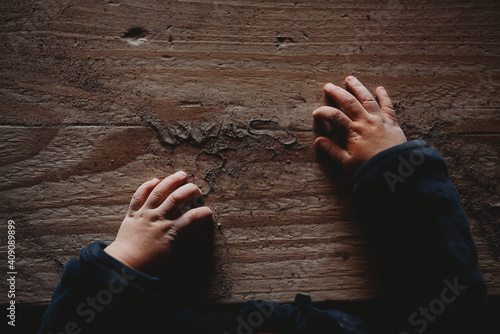 Dimpled baby hands on wooden board full of sand photo