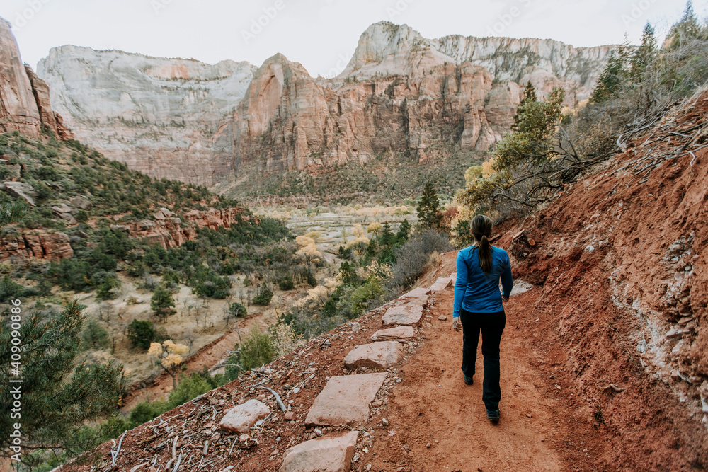 Female hiker walks along red dirt trail in Zion National Park, Utah Female hiker walks along red dirt trail in Zion National Park, Utah