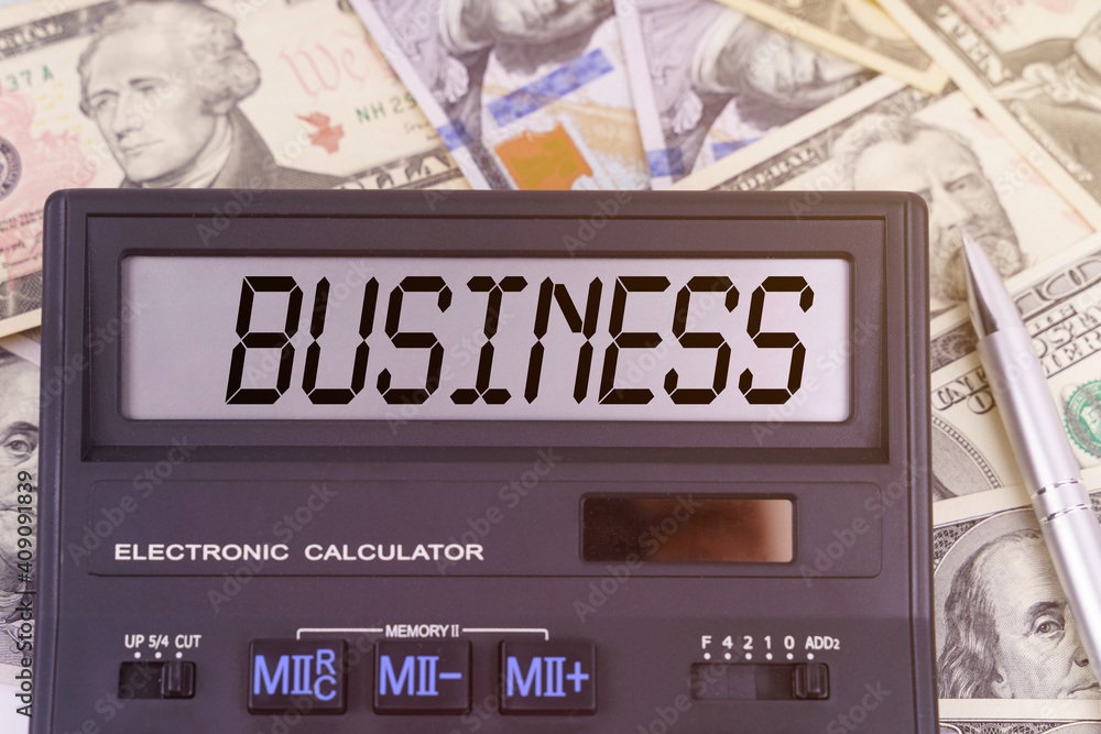On the table are dollars and a calculator on the electronic board which says BUSINESS On the table are dollars and a calculator on the electronic board which says BUSINESS
