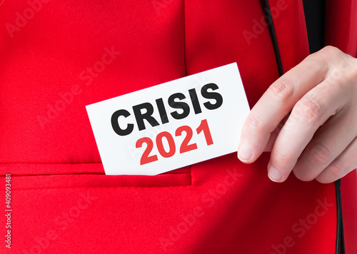 A businessman is holding a card with the text Crisis 2021. Business concept