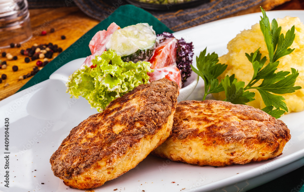 Chicken cutlets, mashed potatoes and vegetable salad on a white plate Chicken cutlets, mashed potatoes and vegetable salad on a white plate