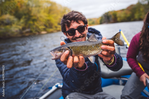 Man holds chub fish out in front of him in a boat photo