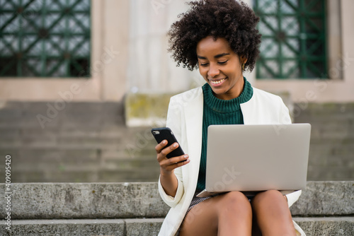 Wallpaper Mural Business woman using her mobile phone and laptop outdoors. Torontodigital.ca