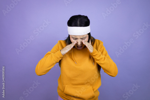 Young latin woman wearing sportswear over purple background shouting and screaming loud down with hands on mouth