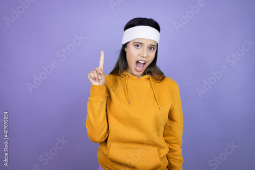 Young latin woman wearing sportswear over purple background smiling and thinking with her fingers on her head that she has an idea.