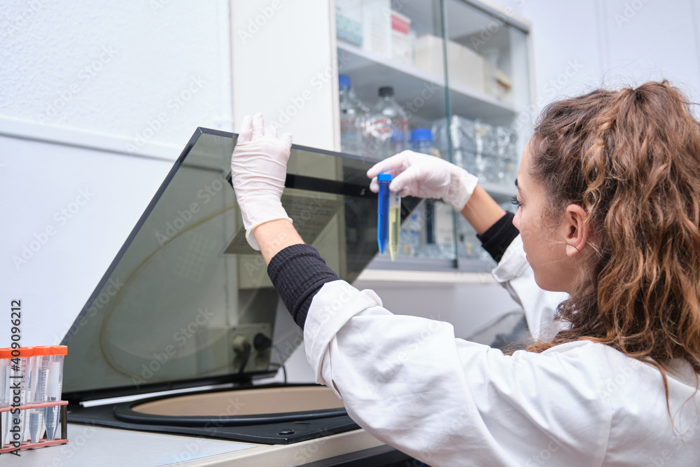 Young female scientist working in a laboratory with a centrifuge. Laboratory research concept. Young female scientist working in a laboratory with a centrifuge. Laboratory research concept.