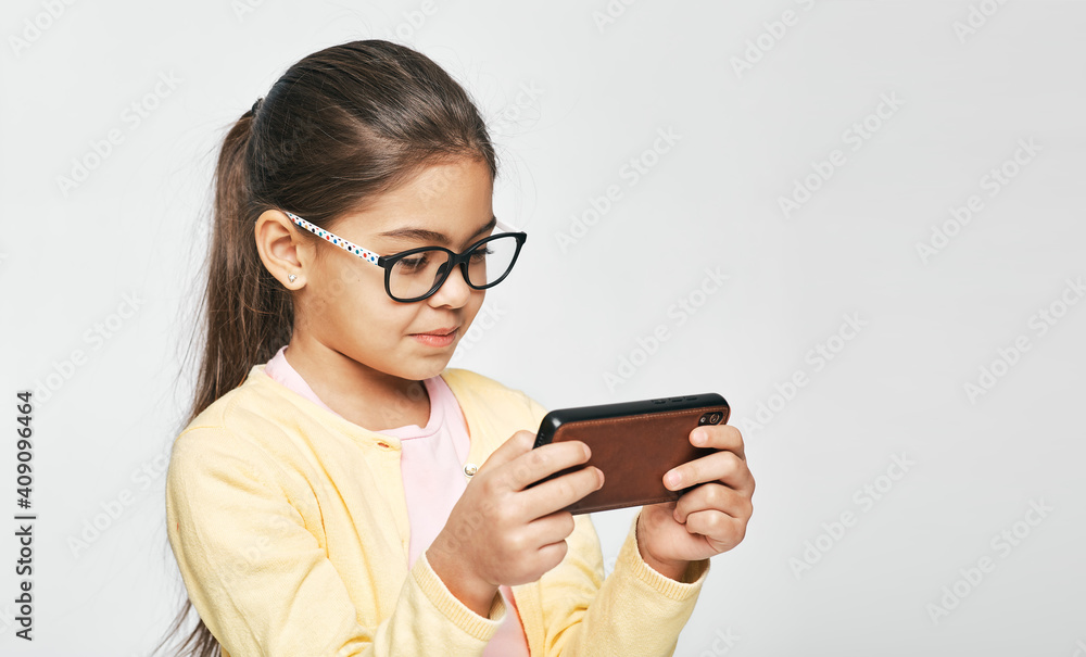 Smartphone use, cause eye damage for children. Child wearing eyeglasses looks at smartphone Smartphone use, cause eye damage for children. Child wearing eyeglasses looks at smartphone