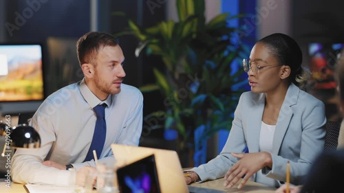 Caucasian and african corporate colleagues gathering around table negotiating partnership agreement and laughing together. Friendshop. Coworkers. photo