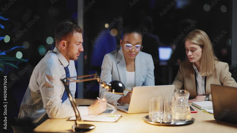 Multi-cultural office people negotiating corporate plans in dark room. Overworking team. Business people. Smart generation. Urban lifestyle. Multi-cultural office people negotiating corporate plans in dark room. Overworking team. Business people. Smart generation. Urban lifestyle.
