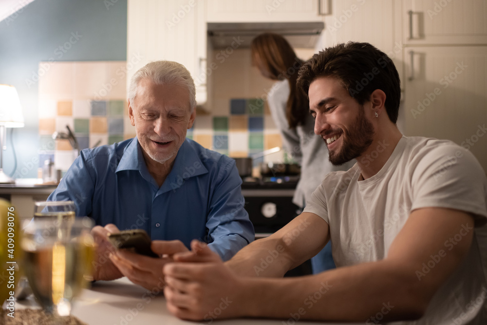 Mature man browsing smartphone near son Mature man browsing smartphone near son