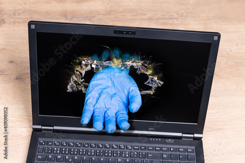 Quadro em tela Laptop detail with imaginary helping hand in blue glove sticking out of punched hole in display