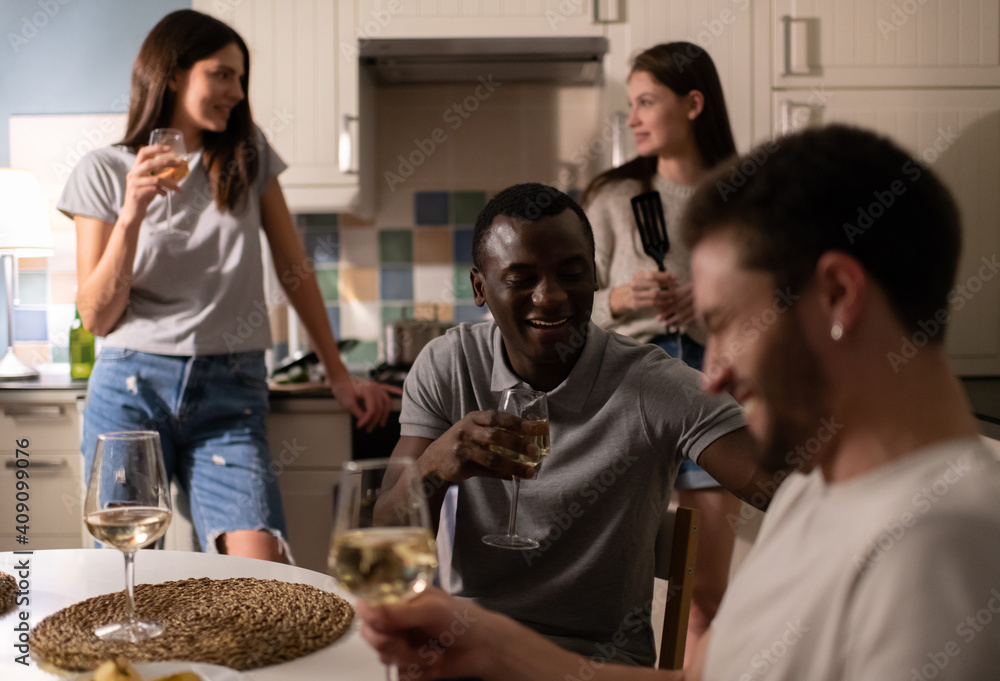 Black man talking with friend during wine party near girlfriends Black man talking with friend during wine party near girlfriends