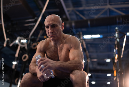 Exhausted senior sportsman with water resting during training photo