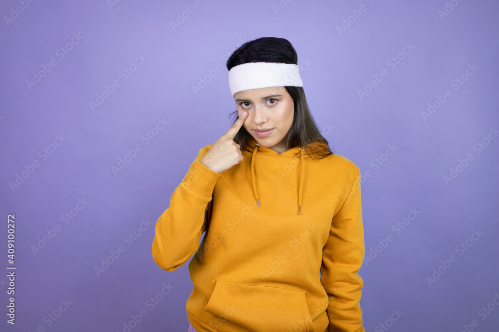 Young latin woman wearing sportswear over purple background Pointing to the eye watching you gesture, suspicious expression Young latin woman wearing sportswear over purple background Pointing to the eye watching you gesture, suspicious expression