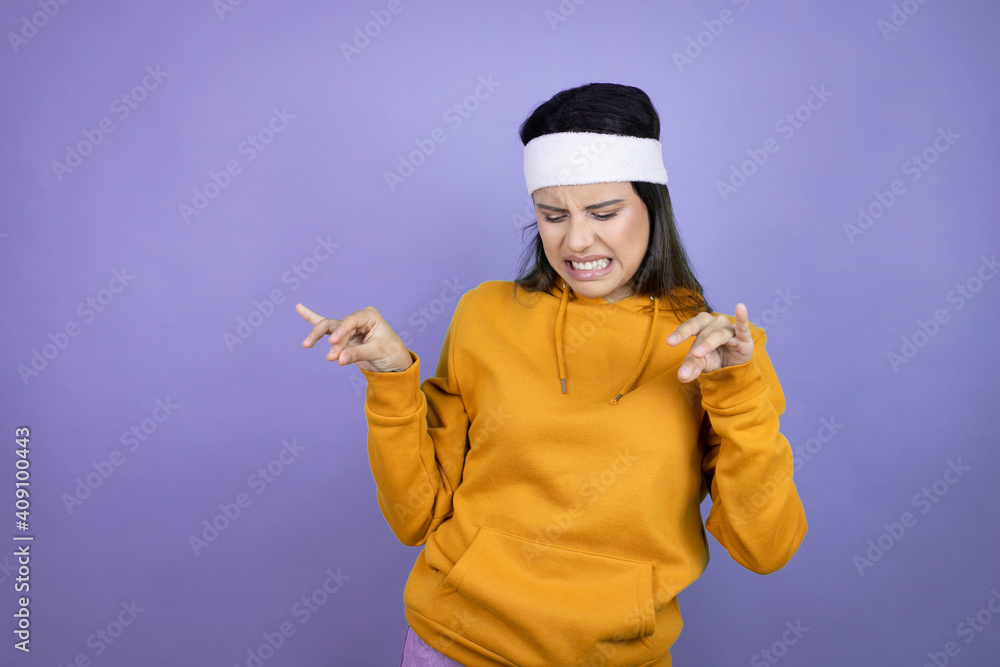 Young latin woman wearing sportswear over purple background disgusted expression, displeased and fearful doing disgust face because aversion reaction. Annoying Young latin woman wearing sportswear over purple background disgusted expression, displeased and fearful doing disgust face because aversion reaction. Annoying