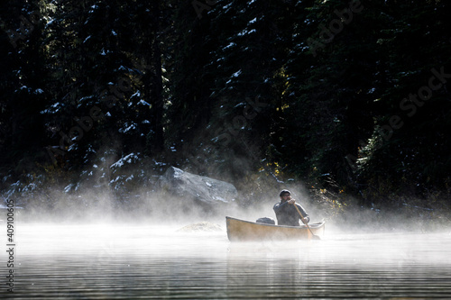 Man boating on a secluded lake on a foggy autumn day photo