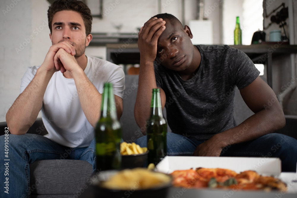 Unhappy diverse friends watching disappointing football match Unhappy diverse friends watching disappointing football match