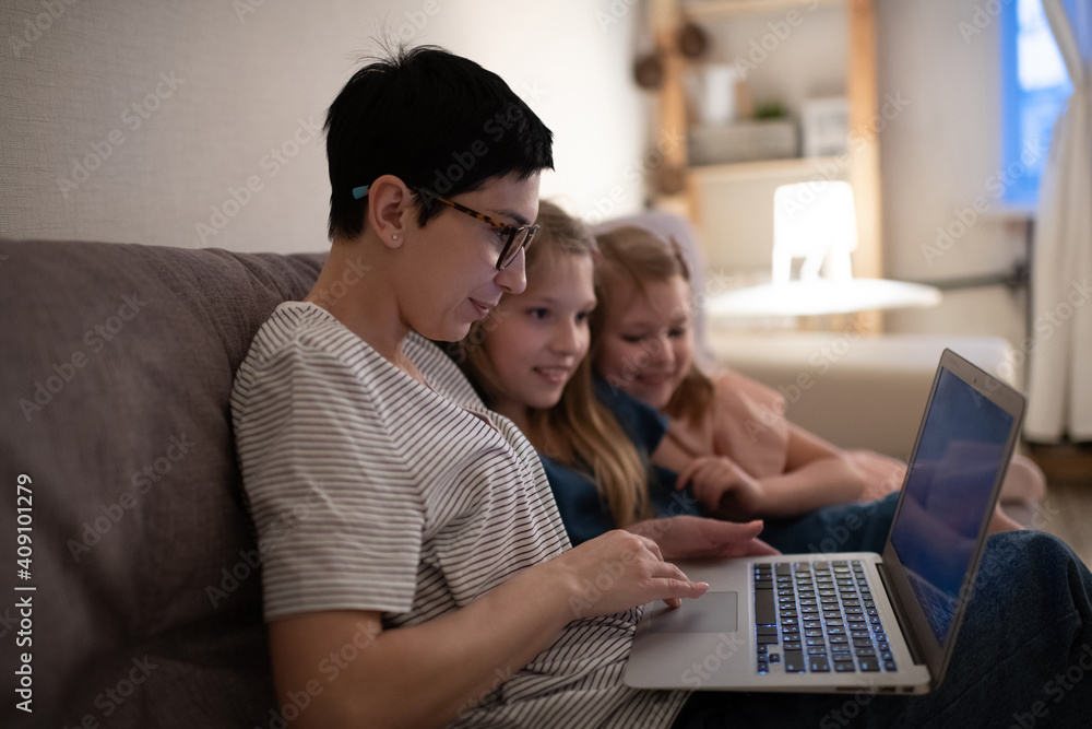 Mother using laptop for work near daughters Mother using laptop for work near daughters