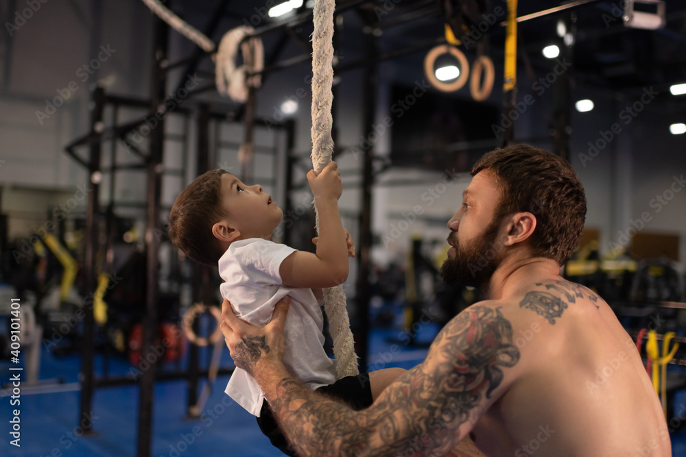 Boy climbing rope with help of strong father Boy climbing rope with help of strong father