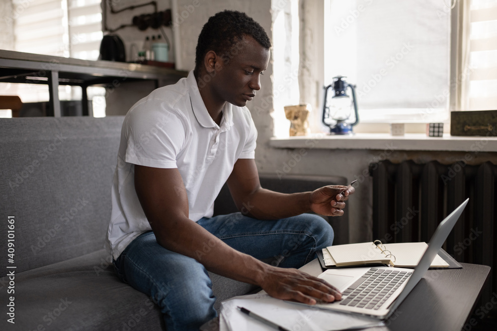 Black man making online order on couch Black man making online order on couch
