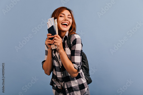 Indoor girl portrait, covering her eyes from happiness, that she will go on journey. Girl holds docs and laughs