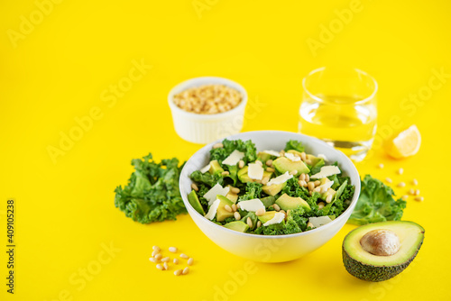 Kale avocado pine nuts cheese salad with lemon dressing in a bowl