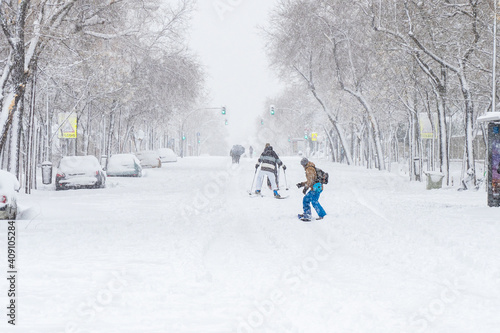 Snowboarder and skiers enjoying in the streets of Madrid City during a historical Snowtorm, Madrid, Spain. photo